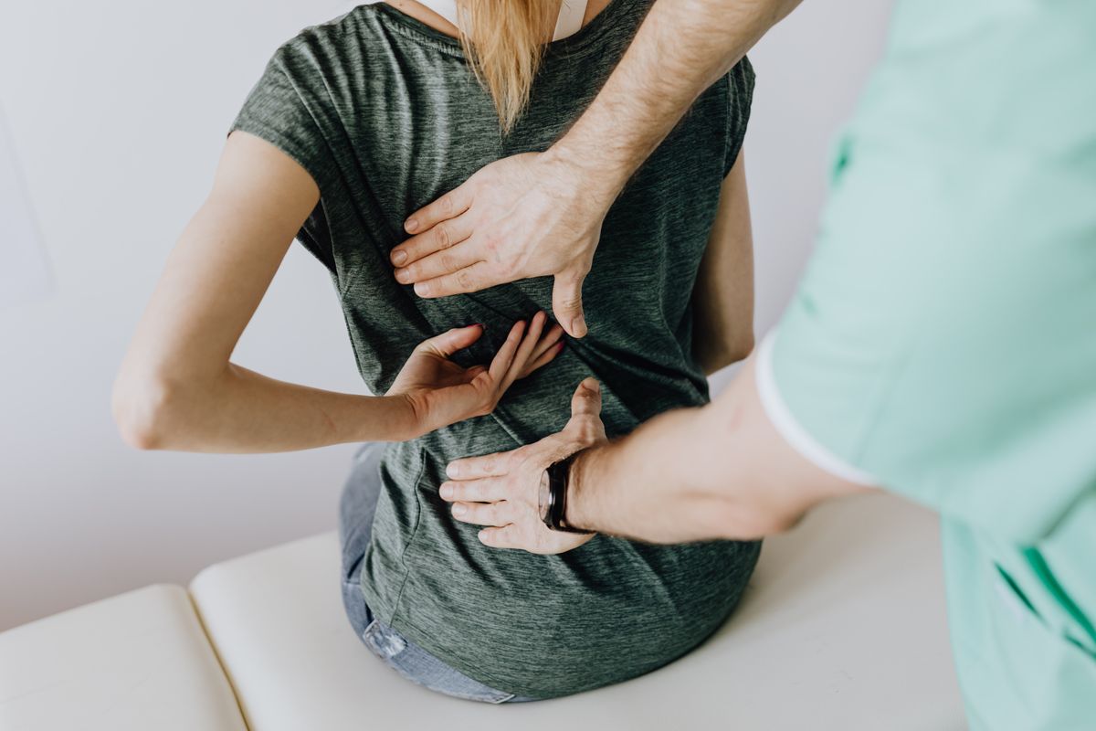 Physical therapist examining a patient's back during a clinic visit
